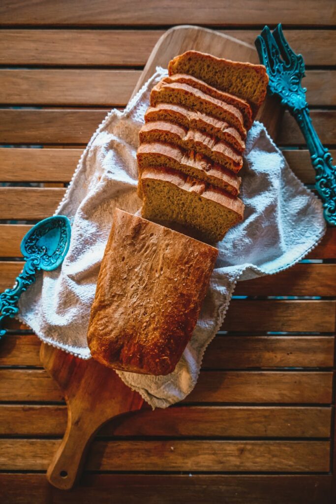 Rustic homemade bread slices on a cutting board with vintage cutlery.
