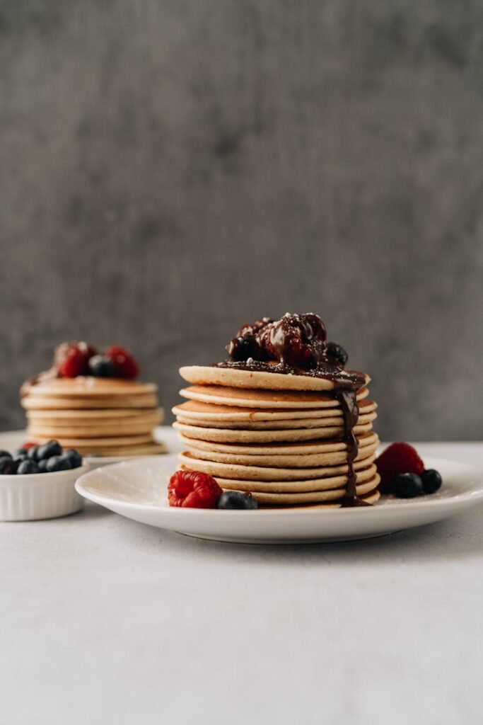 Mouthwatering pancakes with berries and chocolate syrup for a perfect breakfast.
